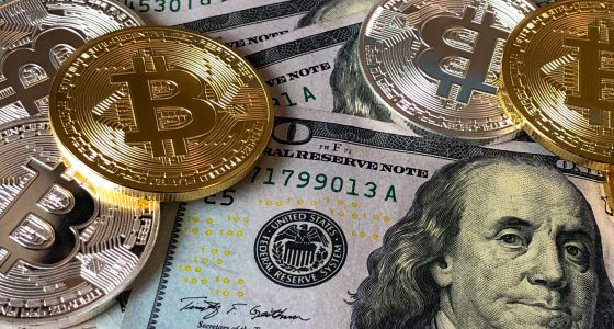 Fyysinen bitcoin-kolikko dollariseteleiden päällä